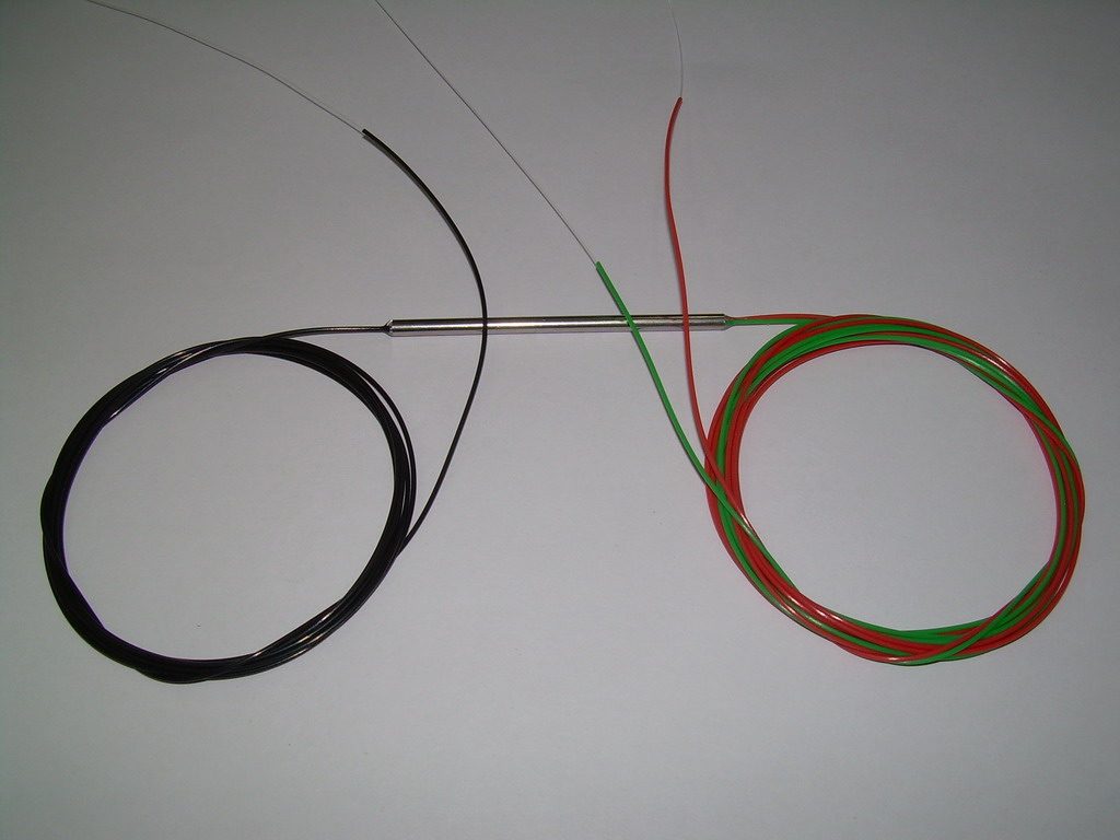 Optik bir WDM birleştiricisi: küçük pasif gövdeden çıkan ince fiber kuyrukçuklar, ayrı dalga boylarındaki ışıkları tek bir lifte topluyor. Metnin multiplexer ve demultiplexer dediği parçanın avuç içine sığan gerçek hâli.