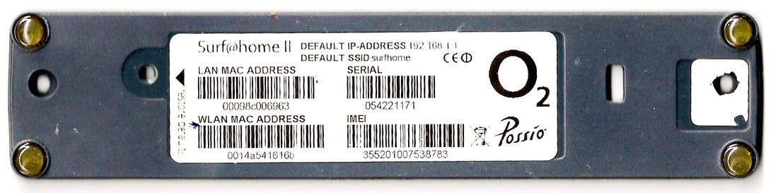 Bir router'ın alt yüzündeki fabrika etiketi: seri numarasının yanında LAN ve WLAN interface'leri için ayrı ayrı basılmış iki MAC adresi. Adresin üretim hattında verildiğini ve her interface'in kendi adını taşıdığını gösteriyor.